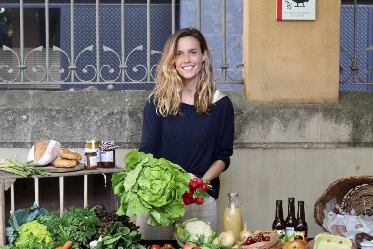 comunidad de consumo mesa con verduras y productos ecologicos chica rubia sonriendo